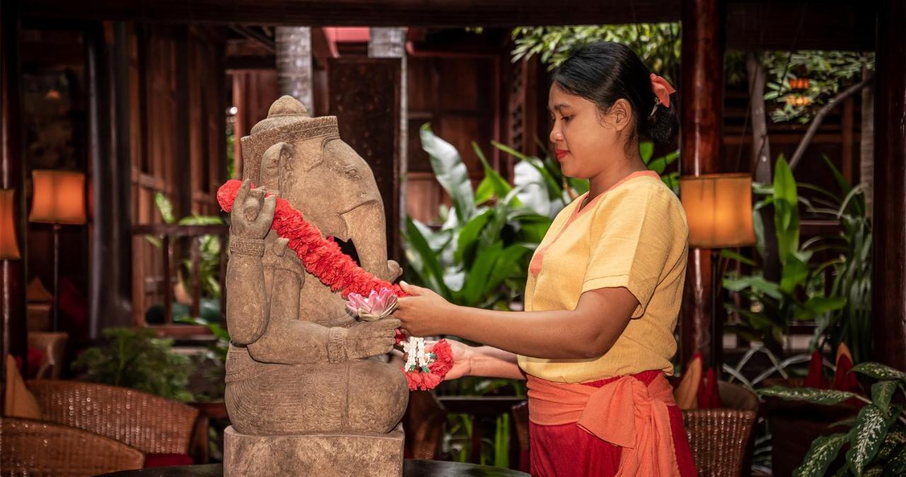Angkor Village Hotel - Small Luxury Hotels Of The World Siem Reap Luaran gambar A woman in Thailand, wearing traditional Thai clothing, garlands a statue of the Hindu god Ganesha.